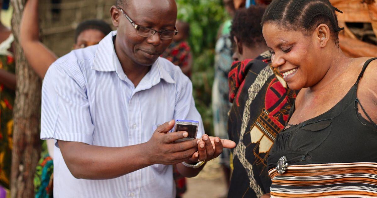 Community worker playing back audio to rural woman in a village.